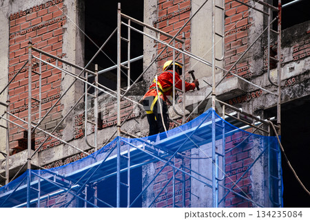 Construction Worker on Scaffolding at Urban Building Site Construction Worker on Scaffolding at Urban Building Site 134235084