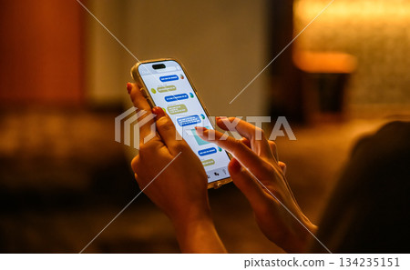 Hands typing a message on a smartphone in the dark Hands typing a message on a smartphone in the dark 134235151