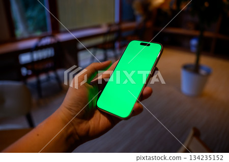 Hand holding a smartphone indoors 134235152