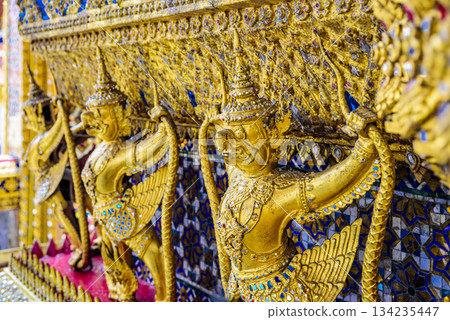 Three golden statues of winged creatures are displayed on a wall 134235447