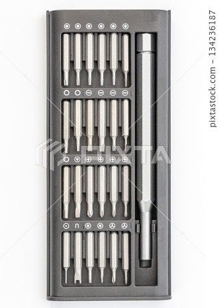 Overhead shot of a black plastic kit containing various sizes and types of silver metal screwdriver bits and a handle. 134236187