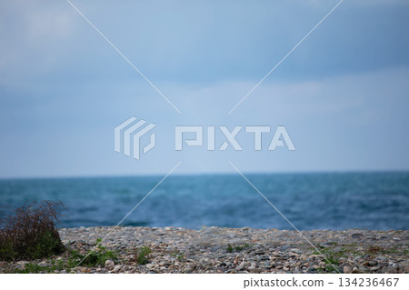 Beach with a small area of ??pebbles and the sea. The sky is cloudy and the water is blue. 134236467