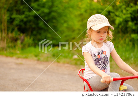Little girl with a tricycle in the park Little girl with a tricycle in the park 134237062