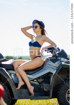 Sexy, slim, pretty, attractive girl in swimsuit on the ATV quad bike. ATV concept. Sexy, slim, pretty, attractive girl in swimsuit on the ATV quad bike. ATV concept. 134237094