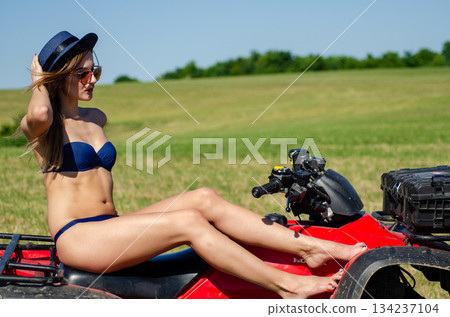 Sexy, slim, pretty, attractive girl in swimsuit on the ATV quad bike. ATV concept. Sexy, slim, pretty, attractive girl in swimsuit on the ATV quad bike. ATV concept. 134237104