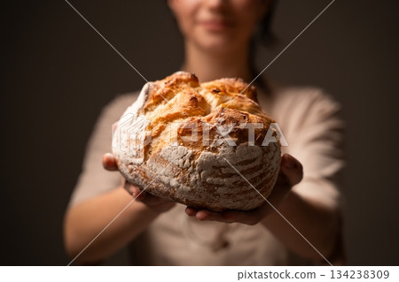Artisan baker presenting rustic handmade bread loaf, showcasing traditional craftsmanship and natural quality 134238309