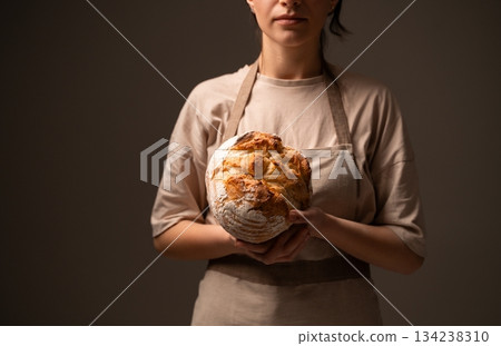 Artisan baker presenting rustic handmade bread loaf, showcasing traditional craftsmanship and natural quality 134238310