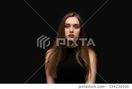 Young woman posing for neutral studio portrait on black background with natural expression and straight posture 134238500