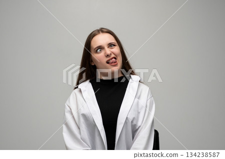 Woman making goofy sideways look with tongue out in humorous expressive studio portrait Woman making goofy sideways look with tongue out in humorous expressive studio portrait 134238587
