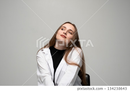 Young woman posing with dreamy expression looking upward in bright minimalist gray studio setting Young woman posing with dreamy expression looking upward in bright minimalist gray studio setting 134238643