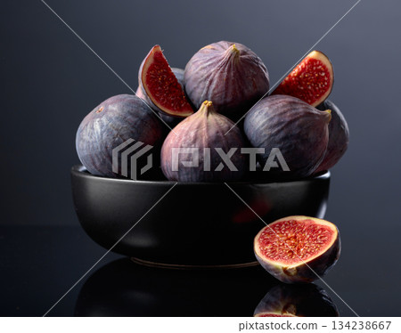 Ripe fig fruit in black dish on a black reflective background. Ripe fig fruit in black dish on a black reflective background. 134238667