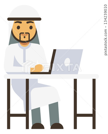 A man wearing a white robe sits at a desk with a laptop 134239010