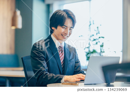 一位商人在辦公室裡一邊看著電腦一邊思考。 134239069