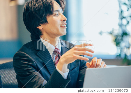 一位商人在辦公室裡一邊看著電腦一邊思考。 134239070