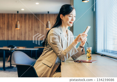 在一家咖啡館經營智能手機的女商人 在一家咖啡館經營智能手機的女商人 134239086