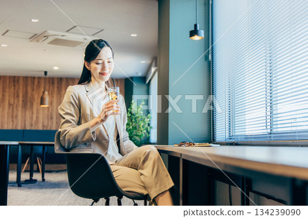 一位女商人正在辦公室喝飲料。 134239090