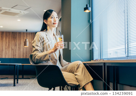 一位女商人正在辦公室喝飲料。 134239091