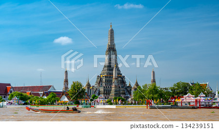 View of Wat Arun across the Chao Phraya River in Bangkok, Thailand, captured on a bright sunny day with the temple iconic spires rising above the shimmering water. View of Wat Arun across the Chao Phraya River in Bangkok, Thailand, captured on a bright sunny day with the temple iconic spires rising above the shimmering water. 134239151