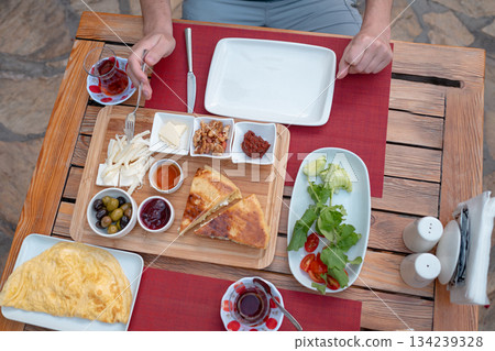Traditional Turkish breakfast spread with fresh bread, olives, cheese, tomatoes, cucumbers, and variety of jams and spreads. Enjoyed in vibrant setting, capturing essence of Turkish morning culture. 134239328