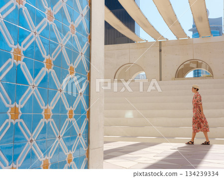 Young woman exploring Qasr Al Hosn Park in Abu Dhabi. Surrounded by lush greenery and historical landmarks, she enjoys the serene atmosphere and Emirati heritage in heart of city. Young woman exploring Qasr Al Hosn Park in Abu Dhabi. Surrounded by lush greenery and historical landmarks, she enjoys the serene atmosphere and Emirati heritage in heart of city. 134239334