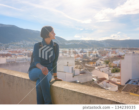 Young woman exploring historic castle in Denia, Alicante province, Spain, scenic views of town below, set against cooler season backdrop. blend of history and tranquility in timeless setting. Young woman exploring historic castle in Denia, Alicante province, Spain, scenic views of town below, set against cooler season backdrop. blend of history and tranquility in timeless setting. 134239335
