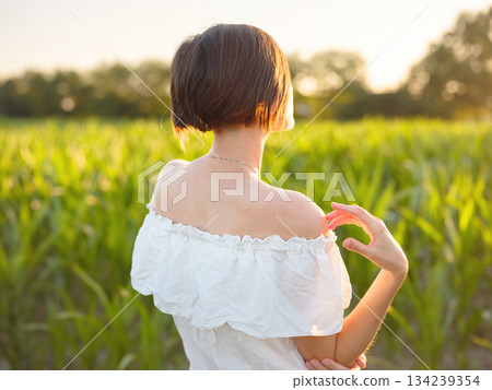 Beautiful woman in white dress standing in summer field during golden sunset in Croatia, warm sunlight, romantic evening mood, natural countryside atmosphere, soft wind and peaceful scene Beautiful woman in white dress standing in summer field during golden sunset in Croatia, warm sunlight, romantic evening mood, natural countryside atmosphere, soft wind and peaceful scene 134239354
