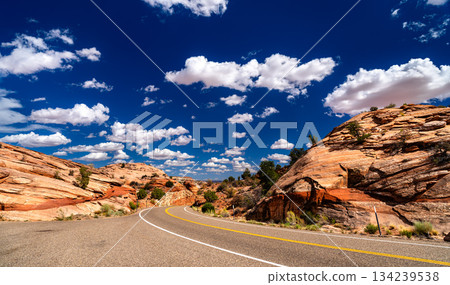 Scenic Byway 12 winds through red sandstone formations in Grand Staircase-Escalante National Monument, Utah. Paved highway curves under blue sky with white clouds Scenic Byway 12 winds through red sandstone formations in Grand Staircase-Escalante National Monument, Utah. Paved highway curves under blue sky with white clouds 134239538