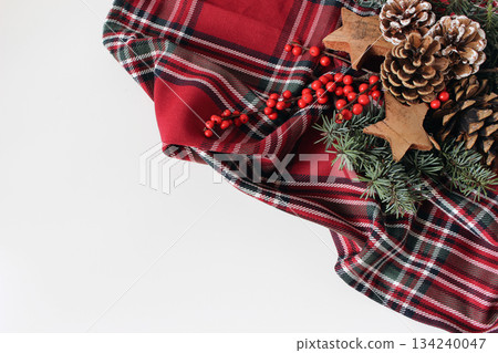 Christmas flat lay still life. Red tartan fabric, pine cones, fir tree branches. Wooden stars, holly berries isolated on white background. Festive holiday decoration Winter season styling, rustic Xmas Christmas flat lay still life. Red tartan fabric, pine cones, fir tree branches. Wooden stars, holly berries isolated on white background. Festive holiday decoration Winter season styling, rustic Xmas 134240047