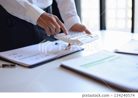 Businessman working in office using calculator. Businessman working in office using calculator. 134240574