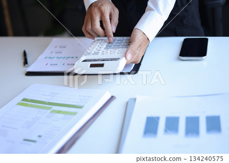 Businessman working in office using calculator. 134240575