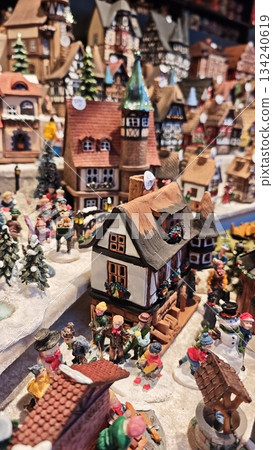 Festive miniature Christmas village scene with detailed houses, snow covered streets and people walking among winter decorations. The image represents holiday atmosphere, community spirit Festive miniature Christmas village scene with detailed houses, snow covered streets and people walking among winter decorations. The image represents holiday atmosphere, community spirit 134240619