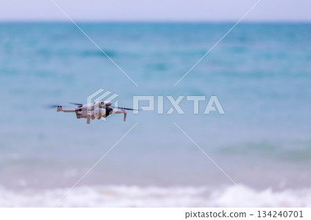 小型無人機在沖繩海灘上空準備起飛進行航拍任務 134240701
