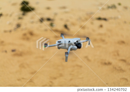 小型無人機在沖繩海灘上空準備起飛進行航拍任務 134240702