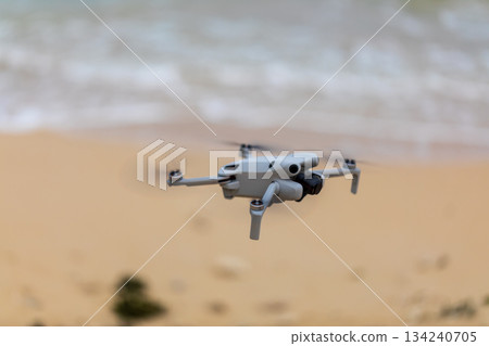 小型無人機在沖繩海灘上空準備起飛進行航拍任務 134240705