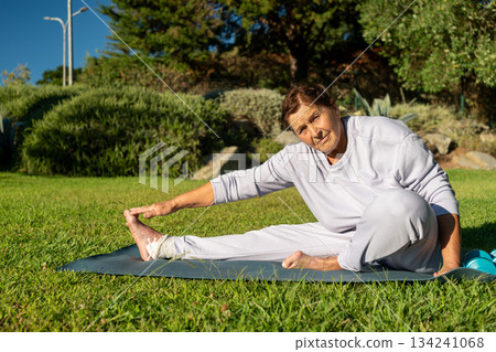 Determined elderly woman touching toes while 134241068