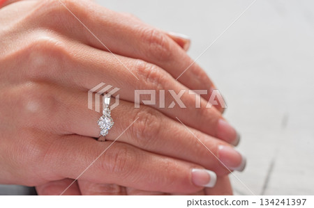 A woman's hand holding a ring with a diamond in the center 134241397