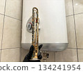 Plumber hand holding a boiler heating element covered with limescale, hard water residue, boiler maintenance and cleaning, scale removal, water heater repair 134241954