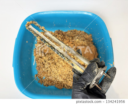 Plumber hand holding a boiler heating element covered with limescale, hard water residue, boiler maintenance and cleaning, scale removal, water heater repair 134241956