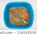 Boiler heating element covered with hard water limescale lying in a bowl with residue after boiler cleaning, damaged heater element, scale buildup concept 134242038
