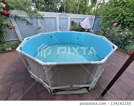 Water is pouring into the blue open-air swimming pool in the yard 134242288