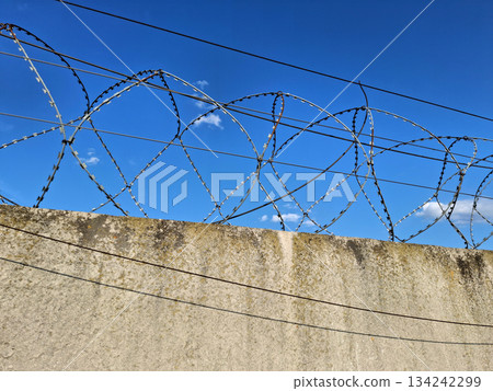 Metal barbed wire is stretched on a concrete fence 134242299