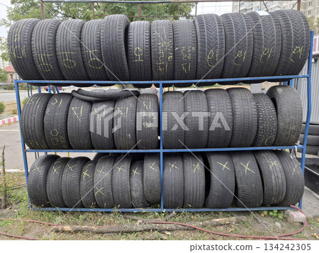 Old black car tires are stacked near a tire shop 134242305