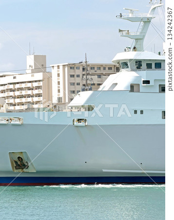 Large white research vessel sails through calm turquoise waters near urban buildings 134242367