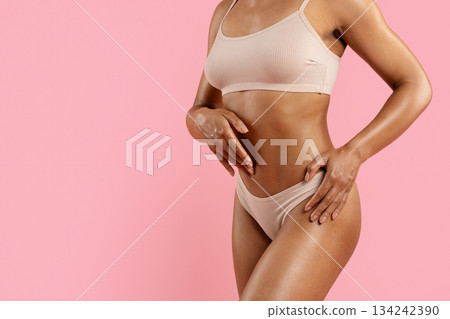 Closeup of black woman toned midsection in underwear on pink studio background Closeup of black woman toned midsection in underwear on pink studio background 134242390