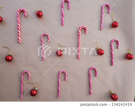 Red and White Candy Canes with Christmas Ornaments on Beige Background 134242419