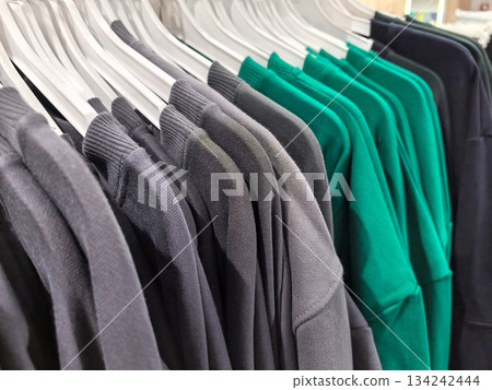 Colorful t-shirts hang on display in a retail store during a sunny afternoon Colorful t-shirts hang on display in a retail store during a sunny afternoon 134242444