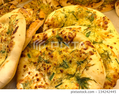 Freshly baked naan bread topped with herbs and spices in a lively market 134242445