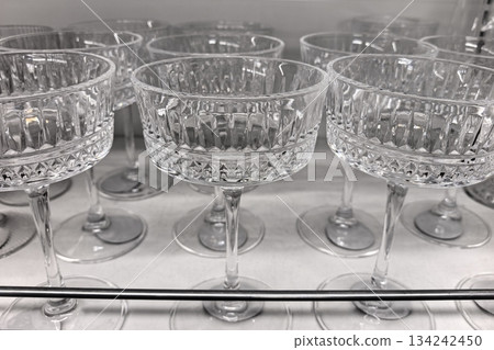 Elegant crystal cocktail glasses showcased in a modern display cabinet Elegant crystal cocktail glasses showcased in a modern display cabinet 134242450