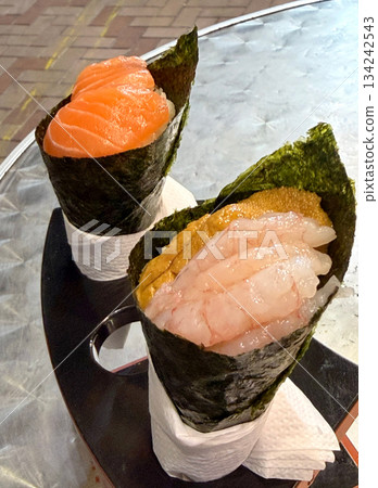 Two delicious temaki sushi cones, one with salmon and the other with shrimp and uni 134242543
