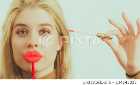 Woman applying lipstick or lip gloss 134243025